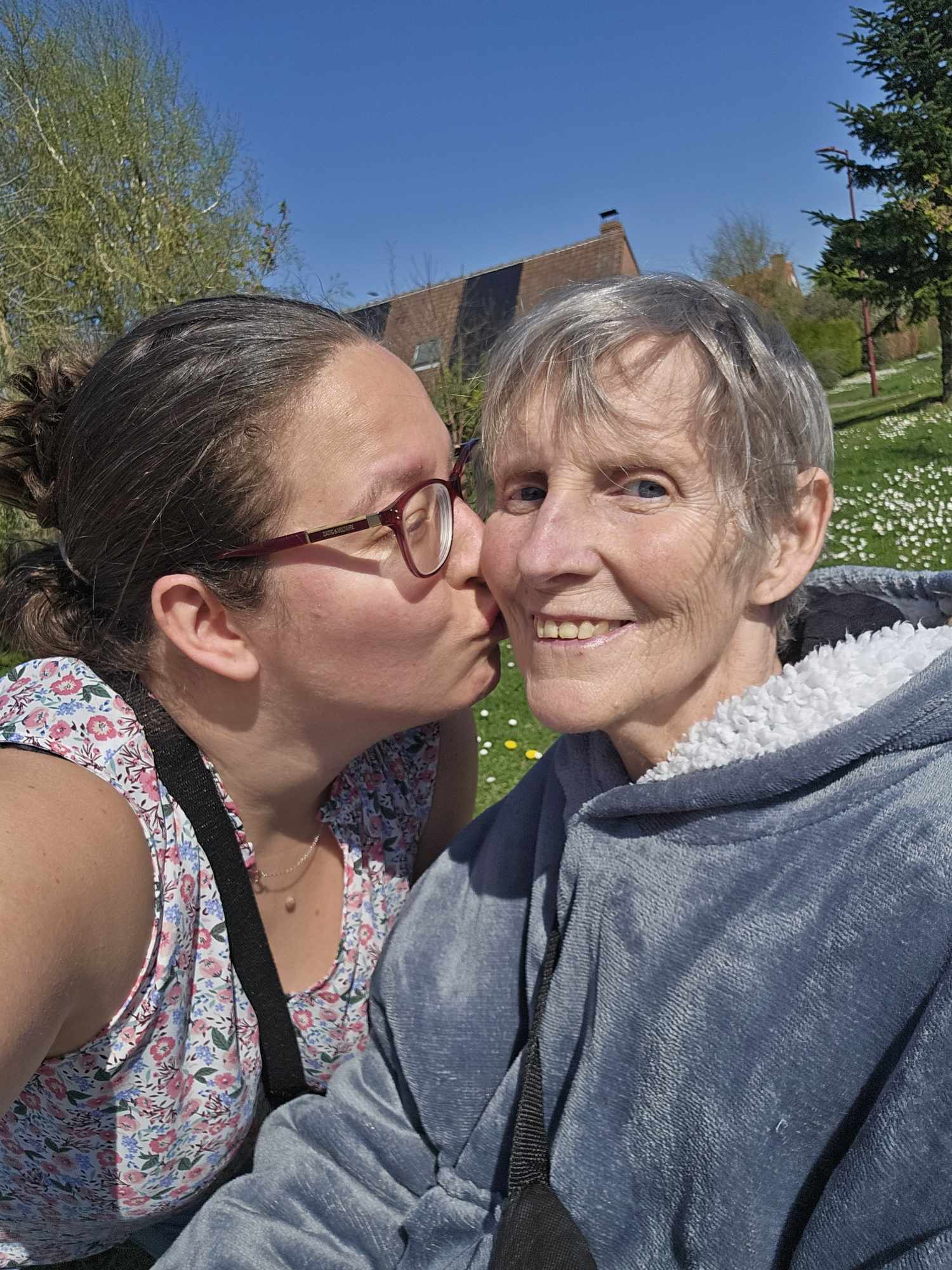 Marie-Ange embrasse sa fille Grégorine sur la joue en plein air